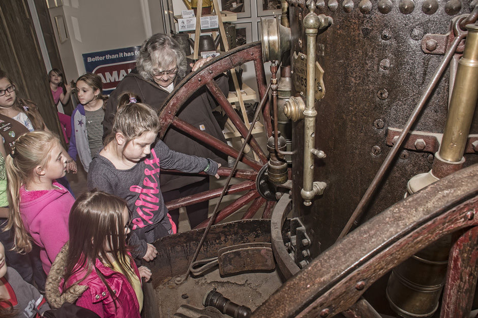 Sherri Schulze and Girl Scouts examine a 19th-century wheeled steam engine.