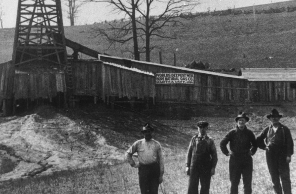 Record-setting West Virginia cable-tool well with drillers standing in front of it.