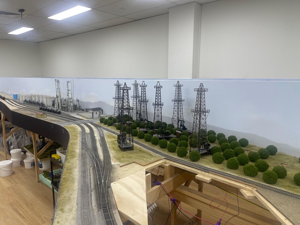 Oil derricks and pumps along model railroad tracks.