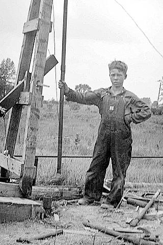 Earl “Red” Perry Jr. of Michigan, 12, stands by his homemade cable-tool rig in 1932.