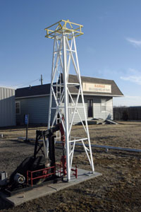 Exterior of oil museum in Great Bend with mini derrick and pump jack in front.