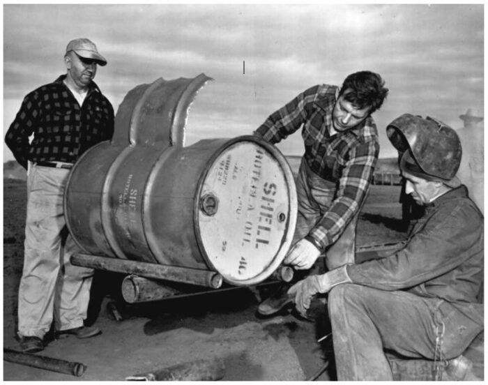 Myron M. Kinley, Paul "Red Adair and a welder examine a nitroglycerin bomb barrel.