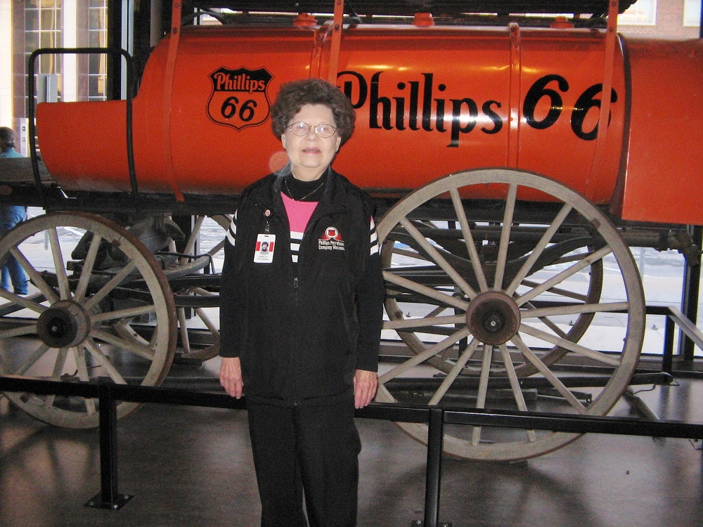 Shirley Patterson stands in front of an orange Phillips 66 petroleum wagon.