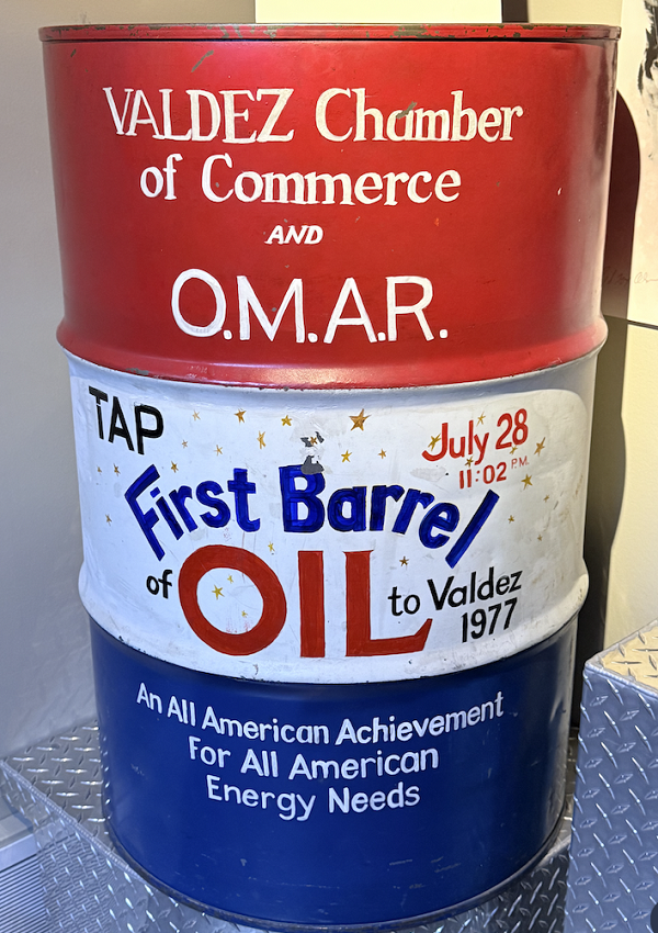 A red-white-and-blue oil drum with "First Barrel of Oil to Valdez."